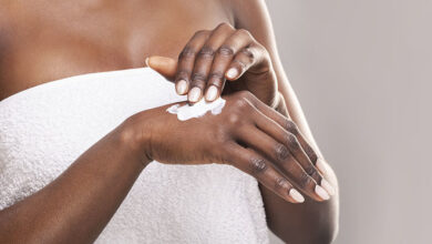 Woman in bathrobe using skin lotion on back of hand