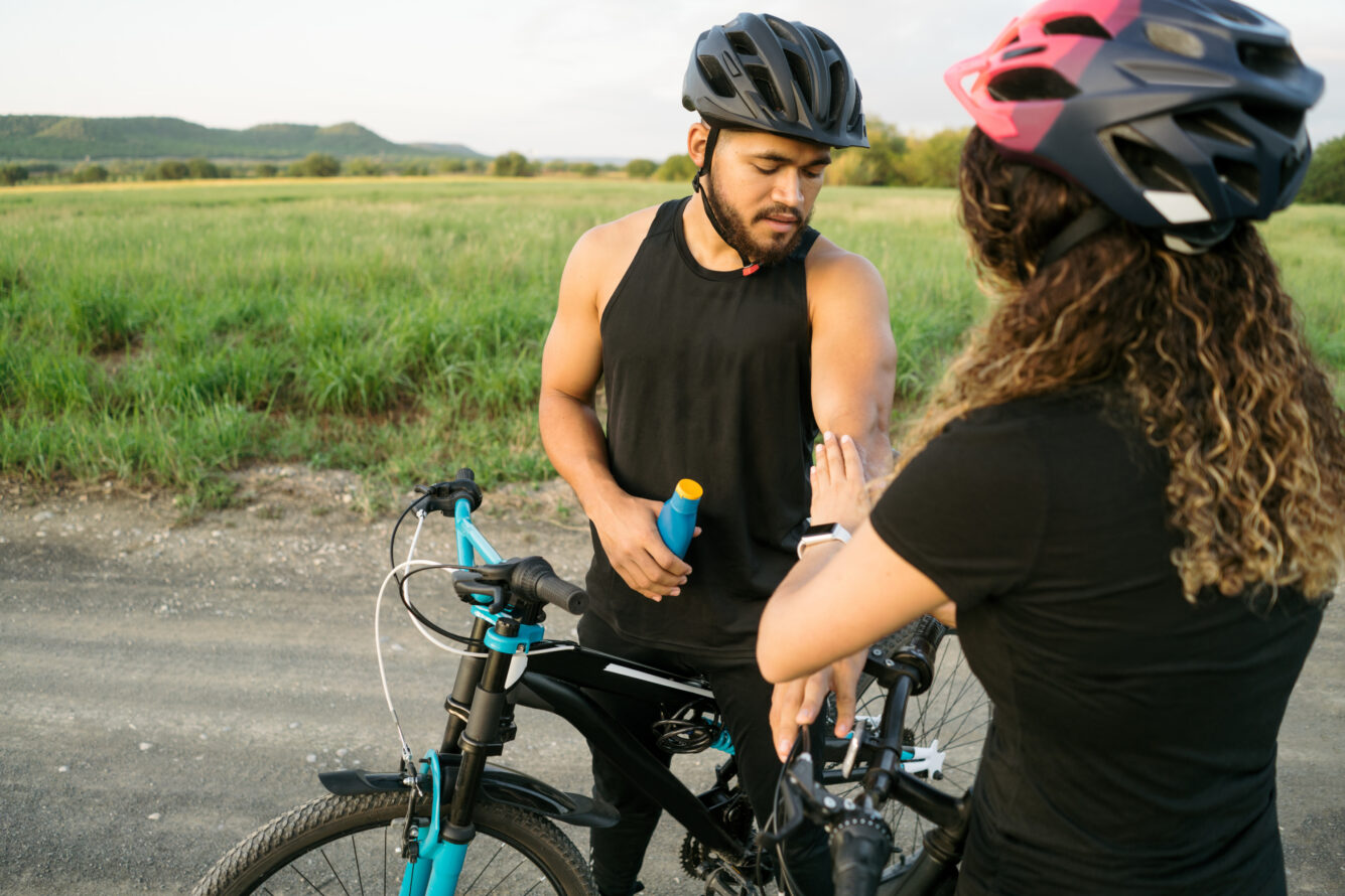A man and a woman standing beside a bicycle on a road